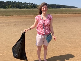 Hannah, Youth Board member, standing on a beach with a rubbish bag