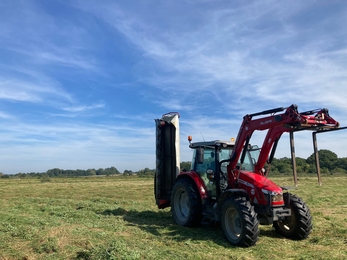 A tractor making hay in a meadow at Carlton Marshes