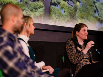 Jenny, Senior Farm Advisor holding a microphone at a panel discussion at the EA Sustain Festival 