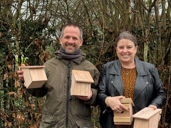 Michael and Clare standing outside holding a nest box in each hand 