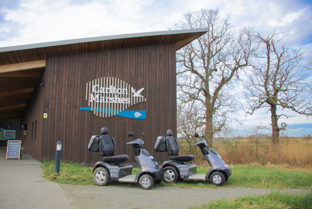 Two mobility scooters parked in front of the Carlton Marshes visitor centre 