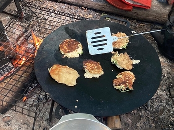 elderflower pancakes cooking on a campfire