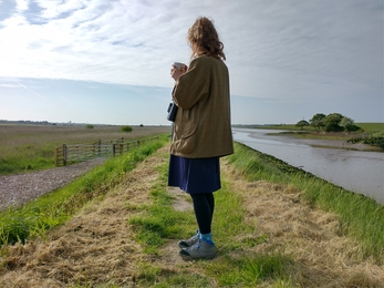 Ellen standing with a cup of tea at Hen Reed Beds