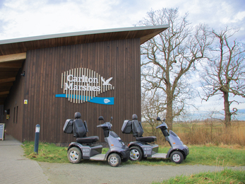 Two mobility scooters parked in front of the Carlton Marshes visitor centre 