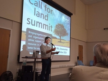 A man presenting in front of a pull down projector screen