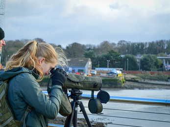 Georgia looking through a scope onto the River Orwell
