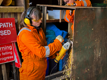 Linsey working on a metal structure in high vis workwear