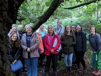 A group of women stood in woodland smiling at the camera