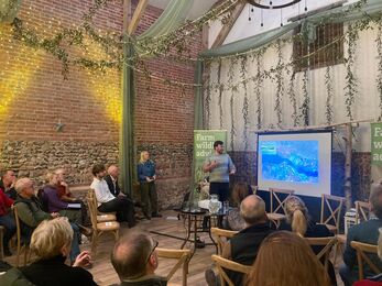 A hall with people sat in rows watching a presentation