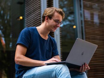 A man sitting outside on a laptop