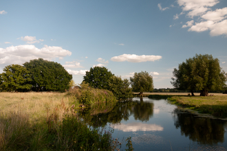 A view of the River Deben winding through the sunny countryside of the Stour Valley in Suffolk