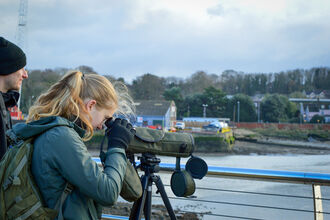 Georgia looking through a scope onto the River Orwell