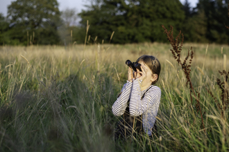 Girl in summer field with binoculars
