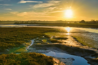 Sunrise over a wetland estuary with pools, mudflats and saltmarsh
