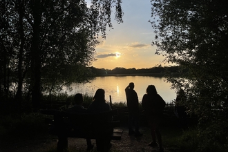 view over a lake as the sun sets with people sillouhetted