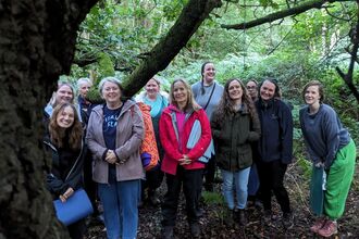 A group of women stood in woodland smiling at the camera