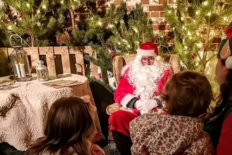 Father Christmas in his grotto at Foxburrow talking with a family