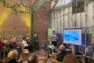 A hall with people sat in rows watching a presentation