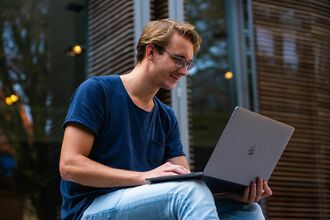 A man sitting outside on a laptop