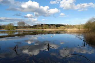 A view across a lake with blue skies and reflections of clouds