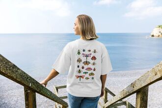 A person walking down some steps at the beach with a colourful t-shirt 