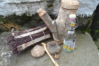 a selection of birch crafts including a carved spoon, a stump of birch wood, and a bundle of birch sticks