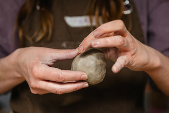 Hands holding a ball of clay 