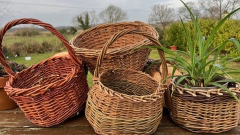 Four woven willow baskets on a bench outside