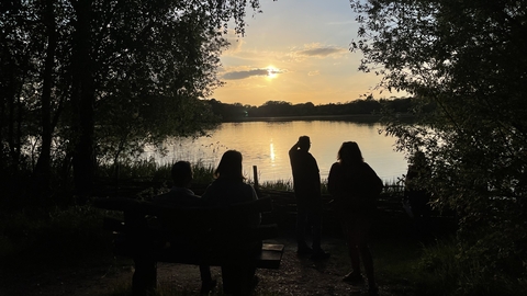 view over a lake as the sun sets with people sillouhetted 