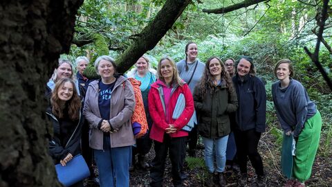 A group of women stood in woodland smiling at the camera
