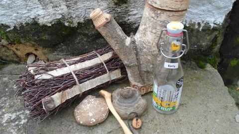 a selection of birch crafts including a carved spoon, a stump of birch wood, and a bundle of birch sticks