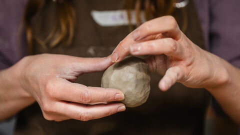 Hands holding a ball of clay 