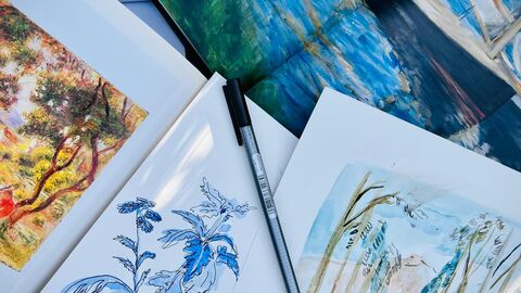 A pile of open books and water colour paintings