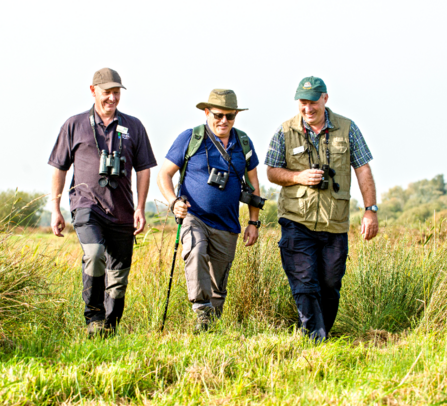 A group of three volunteers walking across the marsh