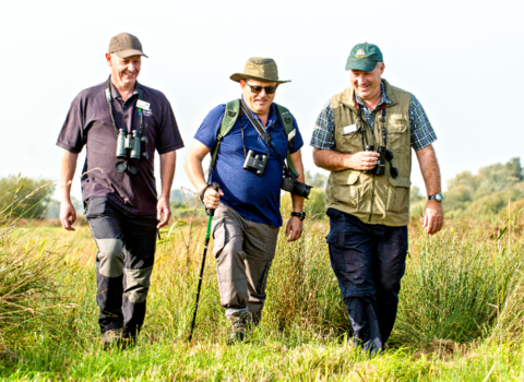 A group of three volunteers walking across the marsh