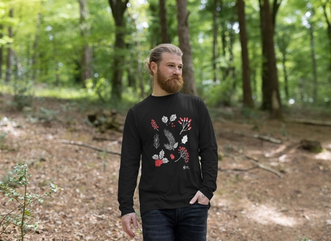 A man walking through a wooded area wearing a festive jumper